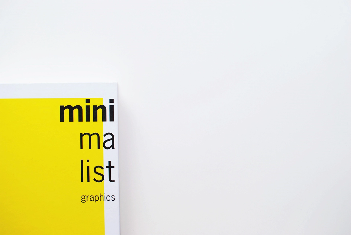 Teilansicht eines Buchcovers mit dem Titel "minimalist graphics" in schwarzer Schrift auf gelbem Hintergrund. Zeigt Arbeit der Mediengestalter:innen.