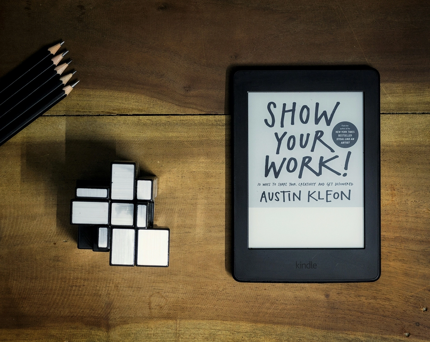 Kindle E-Reader auf Holztisch präsentiert Buchgestaltung von 'Show Your Work!'