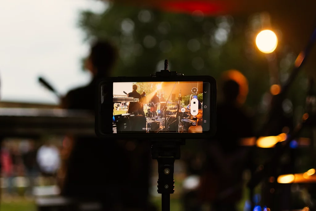 Smartphone filmt die Live-Musikbühne während eines Konzerts beim Festungssommer bei Dämmerung.